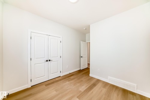 White walls featuring wood-finish flooring and white bi-fold doors - 47 Meadowgrove Lane, Spruce Grove, AB 