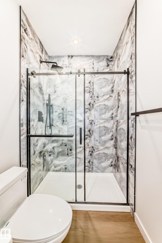 Walk-in shower with clear glass sliding door, black hardware, and patterned wall tile - 47 Meadowgrove Lane, Spruce Grove, AB 