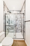Walk-in shower with clear glass sliding door, black hardware, and patterned wall tile - 