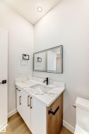 Modern vanity with integrated sink, white cabinetry with gold-tone pulls, a wood-finish side panel, and a matte black faucet - 