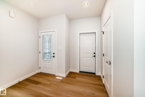 Wood-finish flooring, white walls, recessed ceiling lighting, and white panel doors with black hardware - 47 Meadowgrove Lane, Spruce Grove, AB 