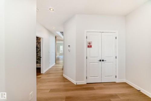 Wood-finish flooring, recessed ceiling lighting, and white paneled double doors with matte black hardware - 47 Meadowgrove Lane, Spruce Grove, AB 