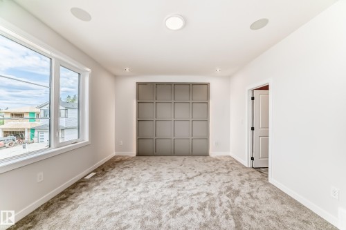Plush carpeting, recessed lighting, large windows, ceiling-mounted speakers, and a paneled accent wall - 47 Meadowgrove Lane, Spruce Grove, AB 
