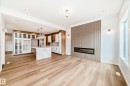 Wood-finish flooring throughout, kitchen with a large island and pendant lighting, built-in cabinetry, linear electric fireplace, and expansive windows - 47 Meadowgrove Lane, Spruce Grove, AB 