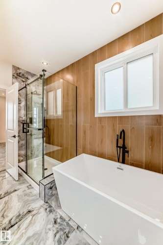 Freestanding soaking tub with a floor-mounted matte black faucet - 47 Meadowgrove Lane, Spruce Grove, AB 