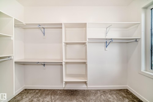 Built-in closet system featuring multiple shelving units, hanging rods, and a window for natural light - 47 Meadowgrove Lane, Spruce Grove, AB 