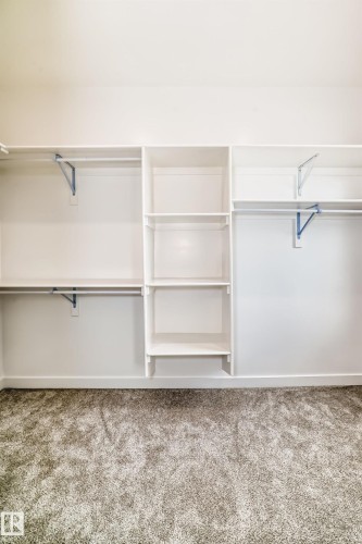 Built-in white shelving and hanging rods providing storage, complemented by gray carpeting - 47 Meadowgrove Lane, Spruce Grove, AB 