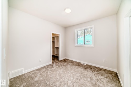 Neutral-toned walls, plush carpet flooring, recessed ceiling light fixture, single window with white trim, and a walk-in closet with built-in shelving - 47 Meadowgrove Lane, Spruce Grove, AB 