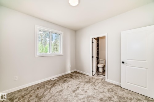 Neutral wall paint, plush carpeting, white trim, white interior doors with matte black hardware, and a window providing natural illumination - 47 Meadowgrove Lane, Spruce Grove, AB 