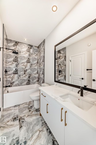 White vanity with gold-tone hardware, a rectangular undermount sink, and a black faucet - 47 Meadowgrove Lane, Spruce Grove, AB 