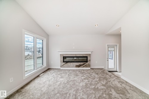 Vaulted ceiling, recessed lighting, and an electric fireplace with a decorative mantel and stone-finish surround - 47 Meadowgrove Lane, Spruce Grove, AB 