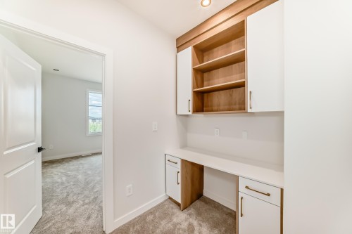 Built-in desk with white countertop, white and wood-finish cabinetry, and wood-finish open shelving - 47 Meadowgrove Lane, Spruce Grove, AB 