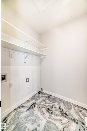 Utility room featuring patterned tile flooring, white walls, and built-in shelving - 47 Meadowgrove Lane, Spruce Grove, AB 