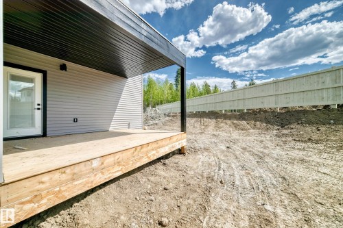 Covered wooden deck with light gray siding, black soffit, and a white privacy fence - 47 Meadowgrove Lane, Spruce Grove, AB 