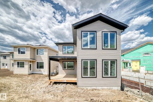 Two-story siding exterior with multiple windows, a covered outdoor deck, and dark-framed windows - 47 Meadowgrove Lane, Spruce Grove, AB 