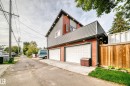 Two-car garage with white panel doors, accented by red-toned horizontal siding and gray vertical siding - 12045 64 Street Nw, Edmonton, AB 