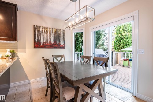 Sliding glass door opening to an outdoor deck, recessed lighting, and a modern rectangular pendant light fixture - 38 Dubonnet Way, St. Albert, AB 