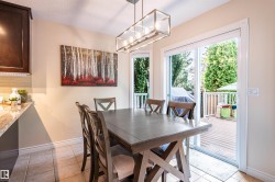 Sliding glass door opening to an outdoor deck, recessed lighting, and a modern rectangular pendant light fixture - 