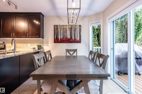 Kitchen with dark wood cabinetry, light-toned backsplash, and a granite-style countertop - 38 Dubonnet Way, St. Albert, AB 