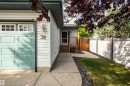 Siding exterior with a light teal garage door, concrete pathway, and an enclosed wooden fence - 38 Dubonnet Way, St. Albert, AB 