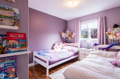 Wood-finish flooring, two large windows with roller blinds, a flush-mount ceiling light fixture, and white wall shelving - 38 Dubonnet Way, St. Albert, AB 