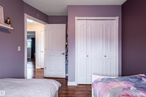 Wood-finish flooring with white trim, white paneled doors, and a built-in closet with bifold doors - 38 Dubonnet Way, St. Albert, AB 