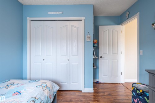 Wood-finish flooring with white baseboards, a textured ceiling, and a white interior door - 38 Dubonnet Way, St. Albert, AB 