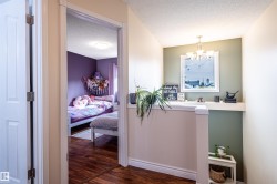 Wood-finish flooring throughout, with a neutral wall palette and a decorative chandelier - 