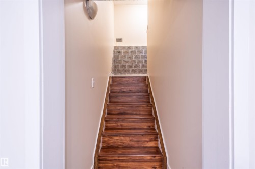 Wood-finish staircase with light wood handrail, neutral wall tones, and tiled wall detail - 38 Dubonnet Way, St. Albert, AB 