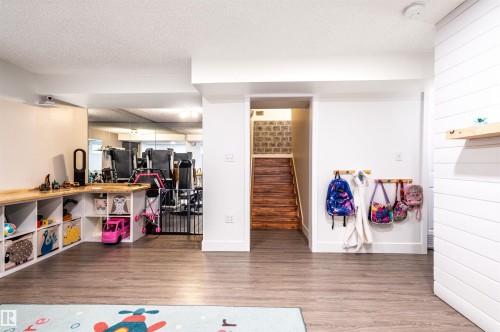 Wood-finish flooring throughout, white shiplap accent wall, built-in storage shelving, and wooden stairwell - 38 Dubonnet Way, St. Albert, AB 