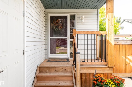 Wood-finish deck with railing, white siding, and an exterior wall lantern - 38 Dubonnet Way, St. Albert, AB 