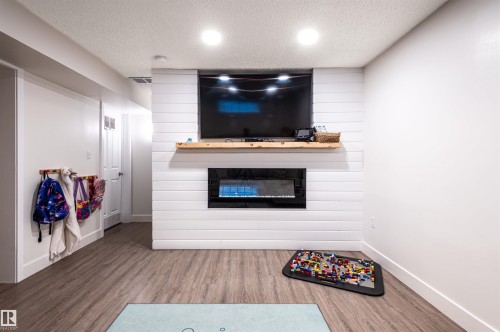 Shiplap accent wall with built-in electric fireplace and wood mantel - 38 Dubonnet Way, St. Albert, AB 