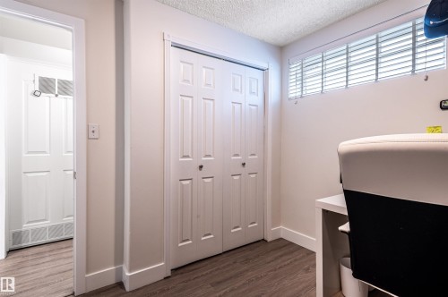 Wood-finish flooring with white baseboards, bi-fold closet doors, and overhead transom window with blinds - 38 Dubonnet Way, St. Albert, AB 