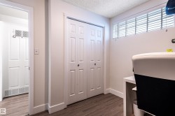 Wood-finish flooring with white baseboards, bi-fold closet doors, and overhead transom window with blinds - 