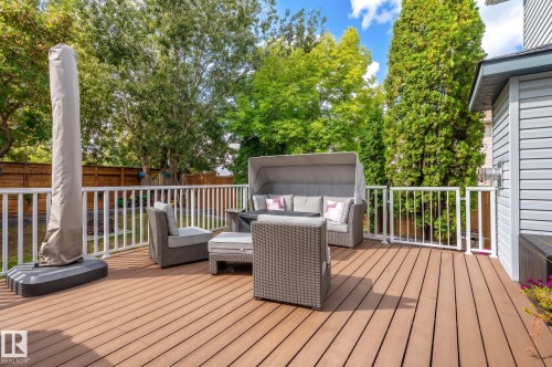Expansive outdoor deck featuring wood-finish flooring, white railings, and lush perimeter trees - 38 Dubonnet Way, St. Albert, AB 