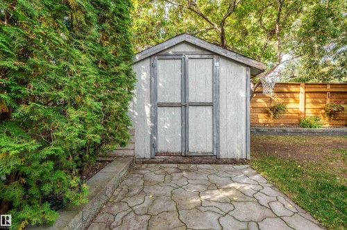 Storage shed with a pitched roof, double doors, and an adjacent paver patio - 38 Dubonnet Way, St. Albert, AB 