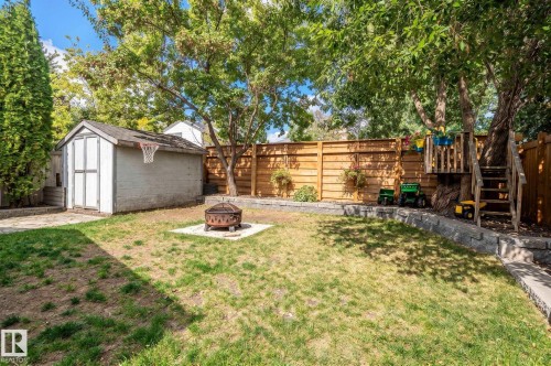 Expansive backyard featuring a storage shed, tiered retaining walls, a fire pit, and a privacy fence - 38 Dubonnet Way, St. Albert, AB 
