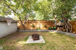Backyard featuring a built-in treehouse with stairs, a basketball hoop attached to a utility structure, a fire pit, and wood fencing - 