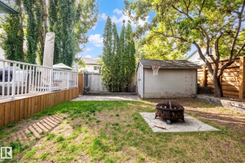 Expansive backyard featuring a wood-plank deck with white railings, a concrete patio area, and a storage shed with an attached basketball hoop - 38 Dubonnet Way, St. Albert, AB 