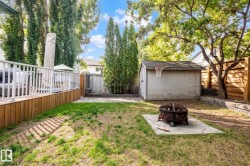 Expansive backyard featuring a wood-plank deck with white railings, a concrete patio area, and a storage shed with an attached basketball hoop - 