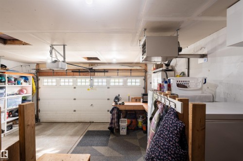 Attached garage featuring an automatic opener, built-in shelving, a dedicated workspace, and overhead radiant heating - 38 Dubonnet Way, St. Albert, AB 