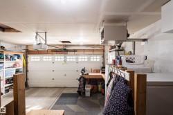 Attached garage featuring an automatic opener, built-in shelving, a dedicated workspace, and overhead radiant heating - 