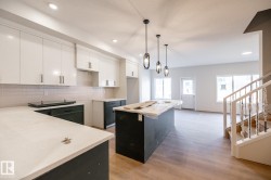 Modern kitchen with crisp white upper cabinetry, dark base cabinetry, light countertops, and a subway tile backsplash - 