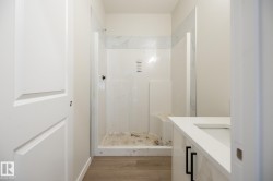 Shower with integrated bench seating, wood-finish flooring, and a vanity featuring an integrated sink, white countertop, and dark hardware - 