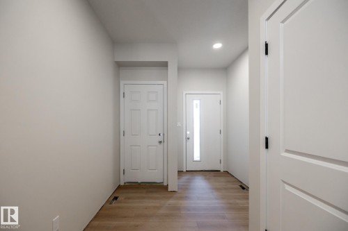 Entryway featuring light wood-finish flooring, recessed ceiling lighting, and a front door with an integrated vertical window - 2358 Muckleplum Way Sw, Edmonton, AB 