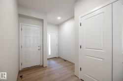 Entryway featuring wood-finish flooring, recessed lighting, white panel doors, and a front door with a full-length sidelight - 