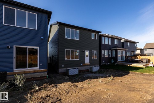 Two-story exterior with dark horizontal siding, white-framed windows, and a sliding glass door - 2358 Muckleplum Way Sw, Edmonton, AB 
