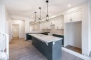 Kitchen featuring white upper cabinetry, dark lower cabinetry, a center island, recessed lighting, and three pendant lights - 2358 Muckleplum Way Sw, Edmonton, AB 