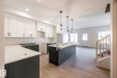 Kitchen featuring an island, recessed lighting, pendant lighting, wood-finish flooring, and white cabinetry - 2358 Muckleplum Way Sw, Edmonton, AB 