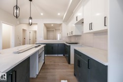 Kitchen featuring an island, two-tone cabinetry with matte black hardware, recessed lighting, wood-finish flooring, and pendant lighting - 